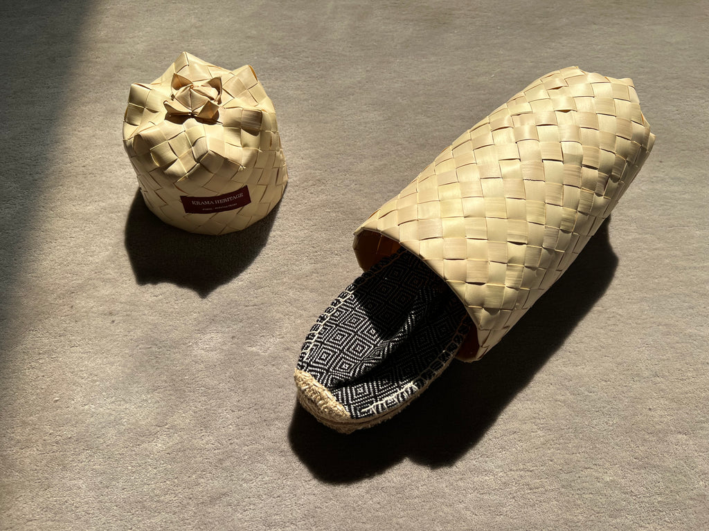 Les espadrilles Diamond Noir Ebène dans leur grand écrin naturel en feuille de palmier