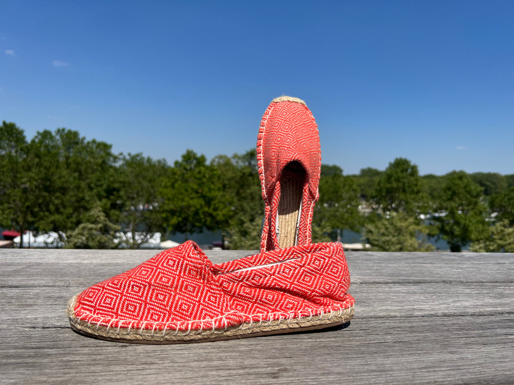 Les espadrilles Diamond Orange Corail dans leur grand écrin naturel en feuille de palmier