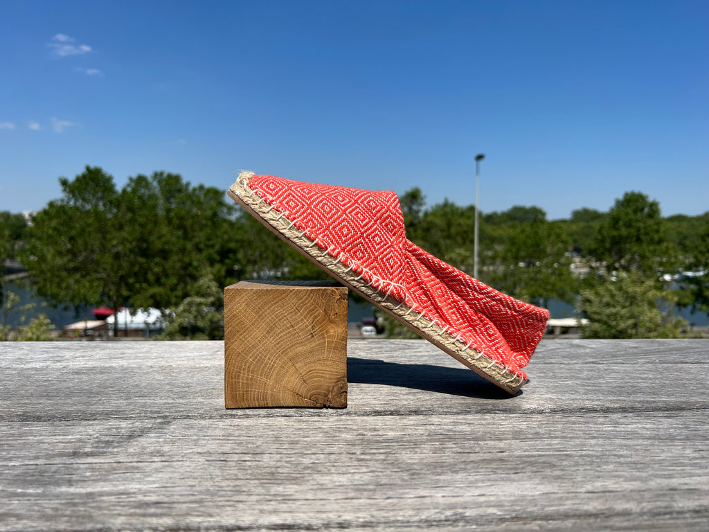 Les espadrilles Diamond Orange Corail dans leur grand écrin naturel en feuille de palmier