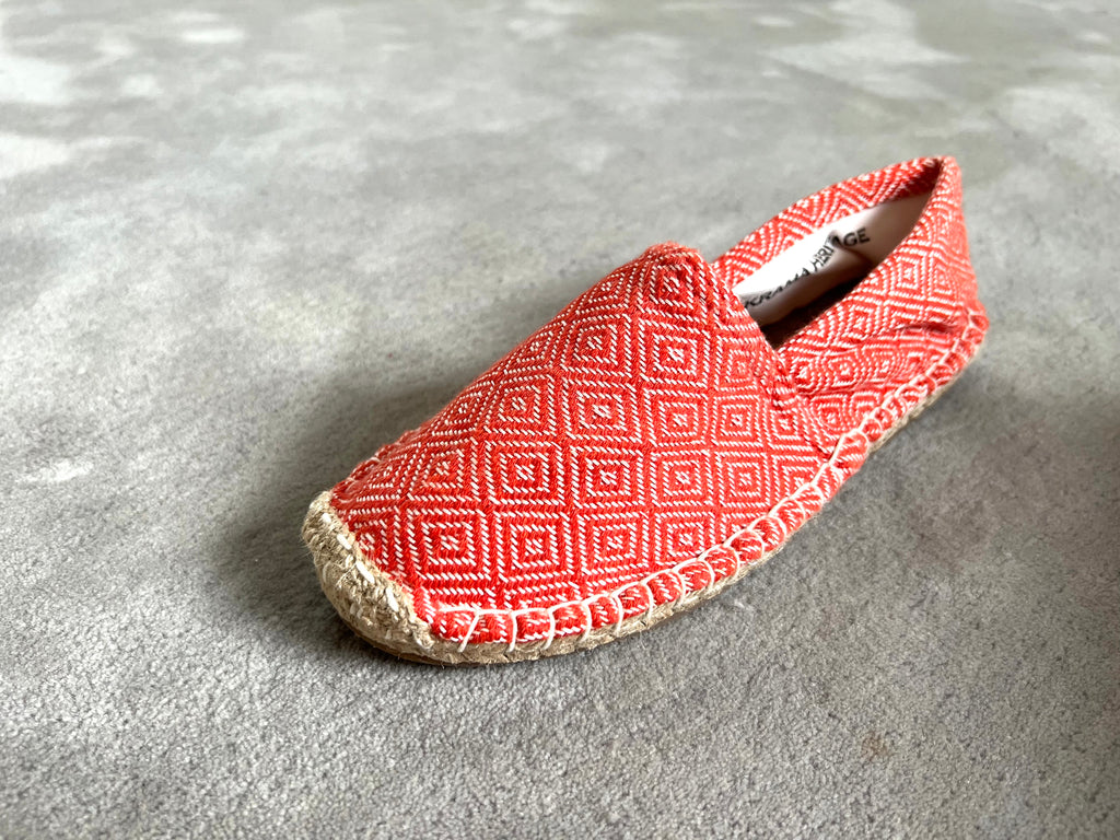 Les espadrilles Diamond Orange Corail dans leur grand écrin naturel en feuille de palmier