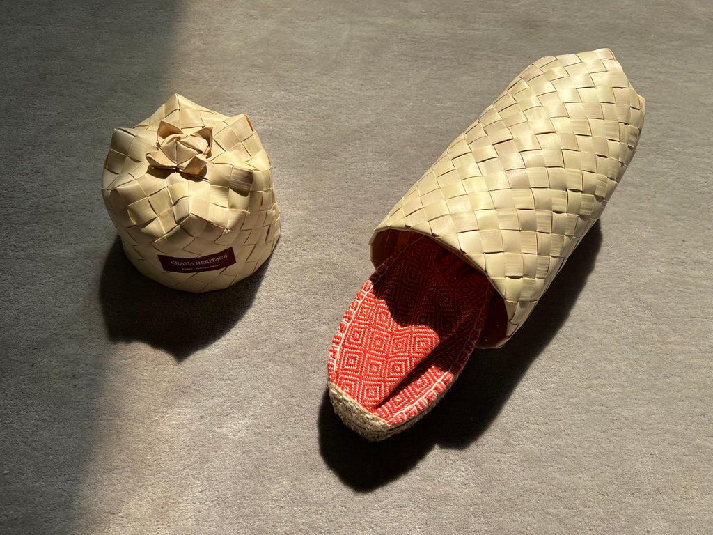 Les espadrilles Diamond Orange Corail dans leur grand écrin naturel en feuille de palmier