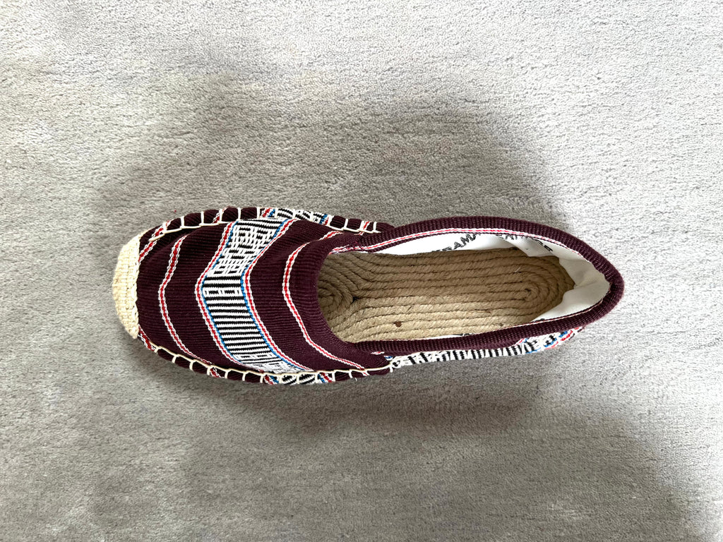 Les espadrilles Ratanakiri Bordeaux dans leur grand écrin naturel en feuille de palmier