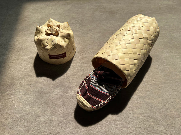 Les espadrilles Ratanakiri Bordeaux dans leur grand écrin naturel en feuille de palmier