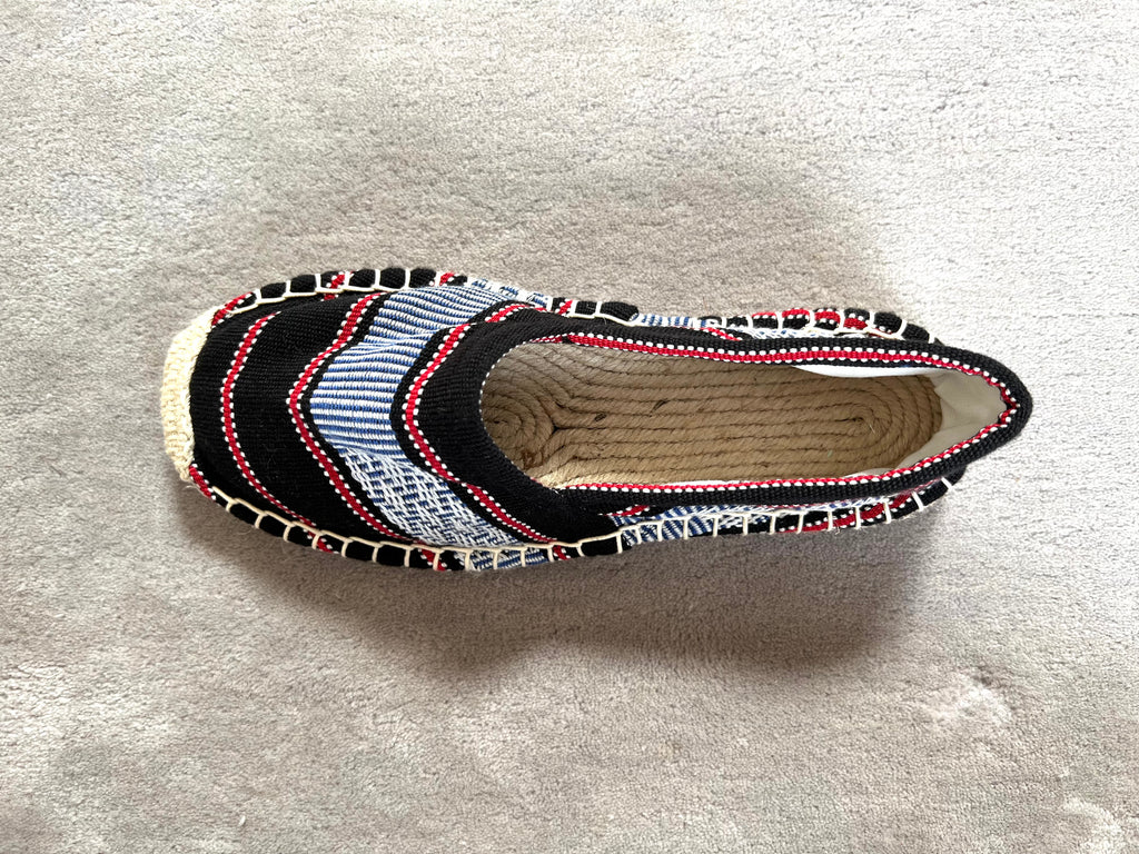Les espadrilles Ratanakiri Réglisse dans leur grand écrin naturel en feuille de palmier