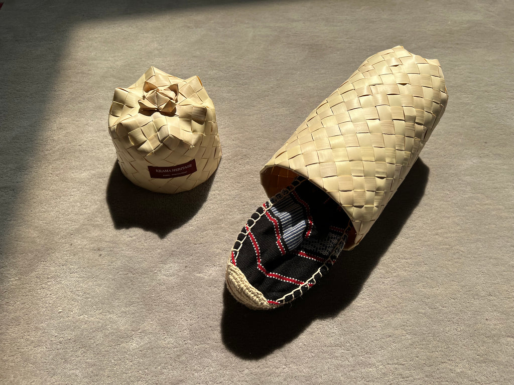 Les espadrilles Ratanakiri Réglisse dans leur grand écrin naturel en feuille de palmier